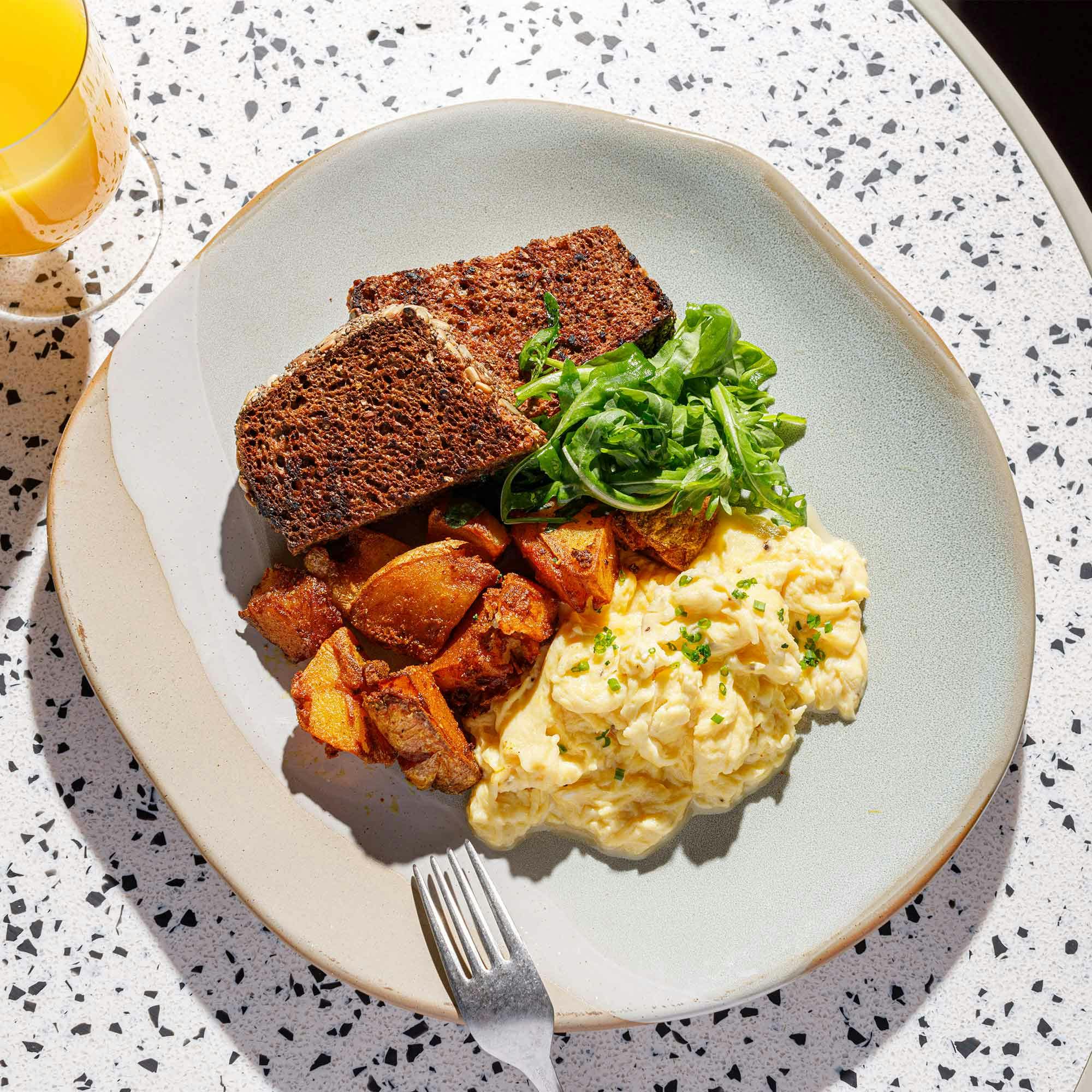Scrambled eggs, breakfast potatoes, wild rocket and toasted rye bread to start the day.